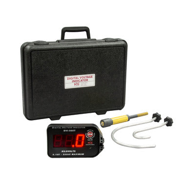 Digital voltage indicator kit displayed on a light gray background. The kit includes a black hard carrying case with a label reading “DIGITAL VOLTAGE INDICATOR,” a compact digital display unit with red LED numerals and control button, a yellow-and-gray probe, and a pair of white test leads with black connectors. The components are arranged in front of the carrying case, showcasing the portable electrical testing equipment and accessories.