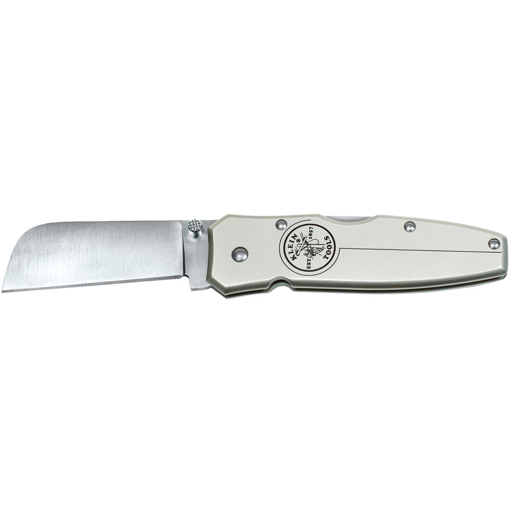 Open folding pocket knife with a satin-finish stainless steel blade and silver metal handle displayed horizontally on a light gray background. The knife features a wide rectangular blade, visible pivot hardware, and a circular logo on the handle reading “Klein Tools Est. 1857” with a lineman graphic. The blade is extended and the handle has a smooth, contoured design with several visible screws.