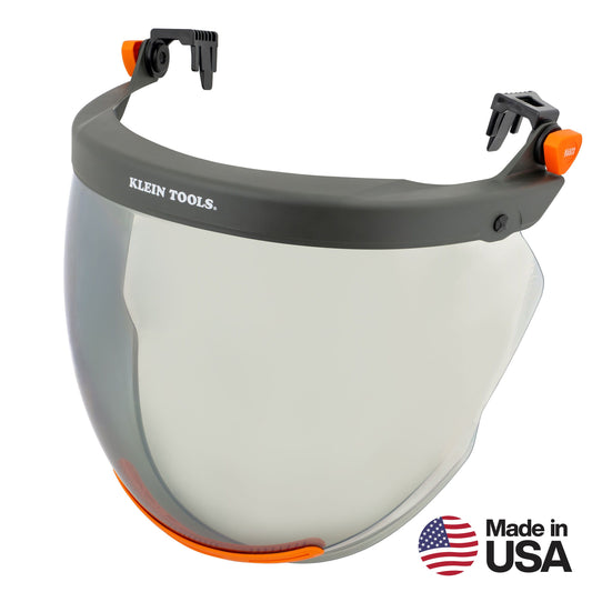 Clear full-face protective shield with a black headgear frame, orange adjustment components, and mounting clips for attachment to a hard hat. The shield features Klein Tools branding on the front and is shown against a light gray background with a “Made in USA” logo in the lower-right corner.