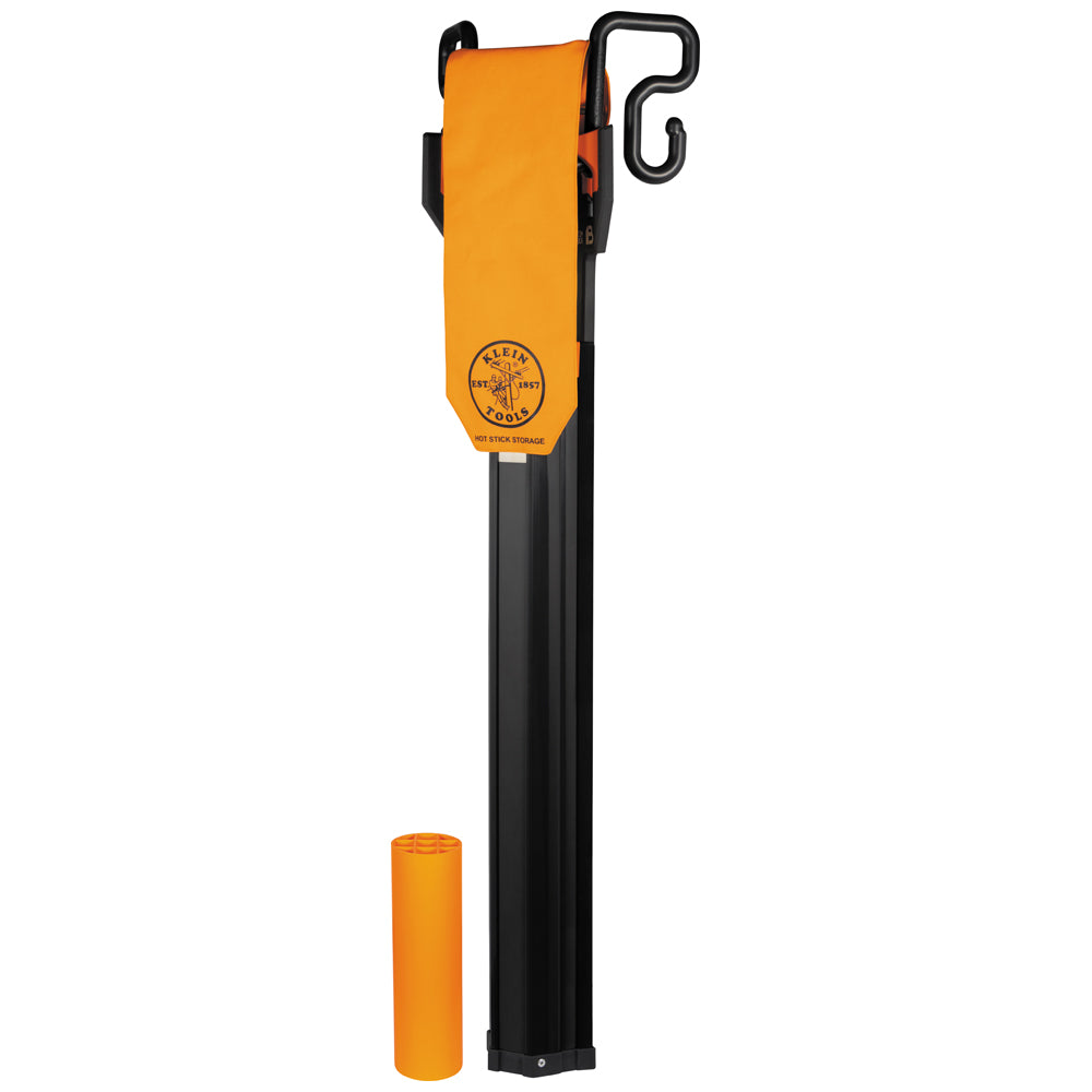 Klein Tools hot stick storage holder featuring a long black tubular body with an integrated hanging hook and an orange protective flap displaying the Klein Tools logo and “Hot Stick Storage” text. An orange cylindrical end cap is shown separately next to the storage holder on a light gray background.