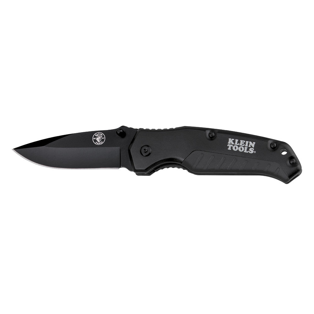 Black folding pocket knife with a matte black blade and handle, shown fully opened against a light gray background. The handle features silver screws, a thumb stud near the blade hinge, and a circular Klein Tools logo printed on the side.
